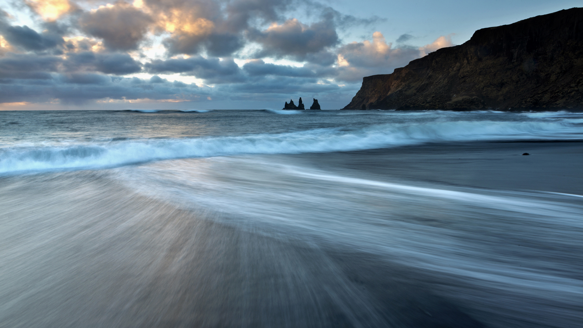 Sea stacks of Reynisdrangar at sunrise from the black volcanic sand beach at Vík í Mýrdal, South Iceland