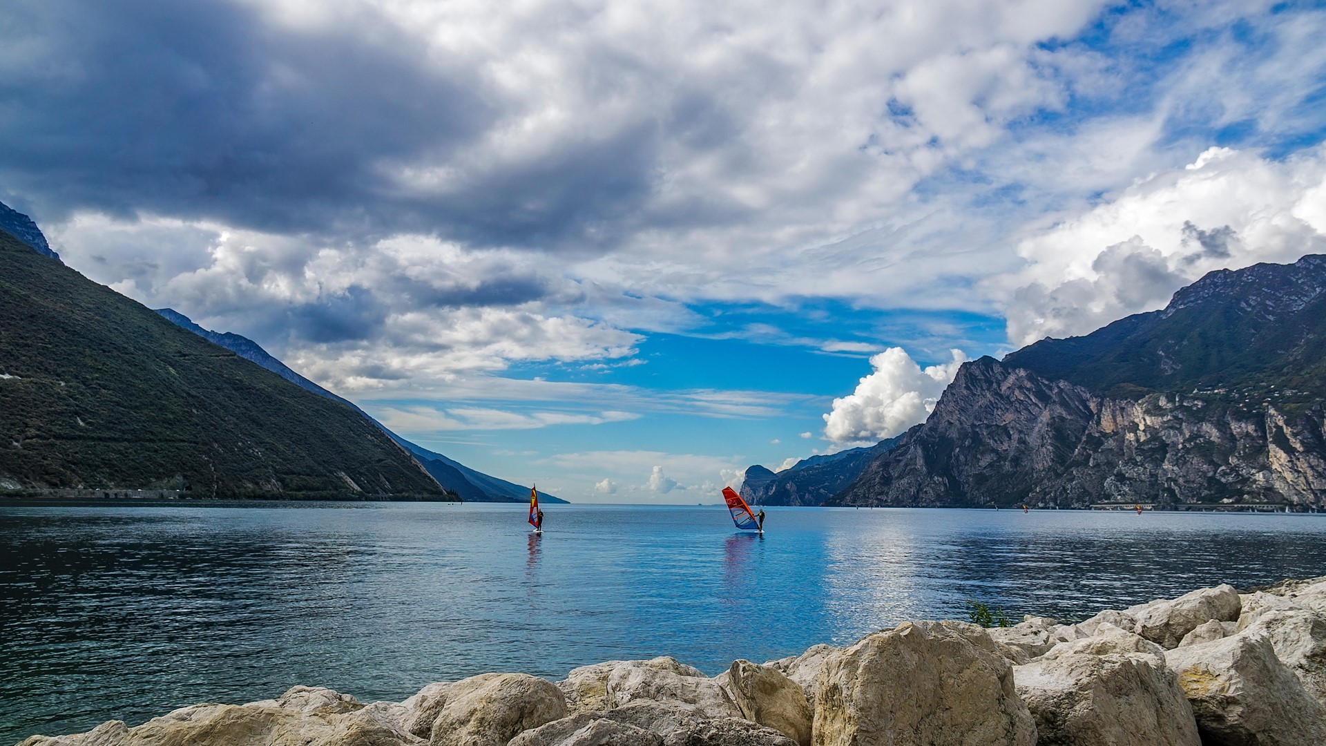 Surfers between mountains on Lake Garda, Italy