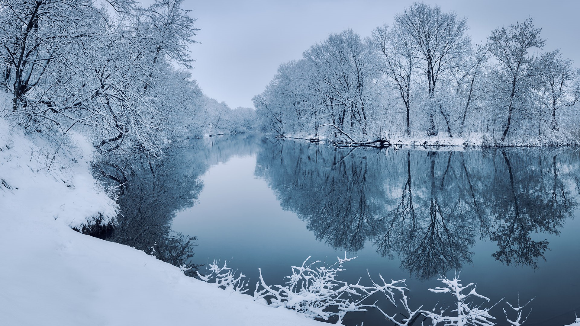 Winter landscape with river in forest at sunset